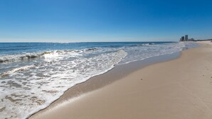 Een strand met heldere lucht en rustige golven.