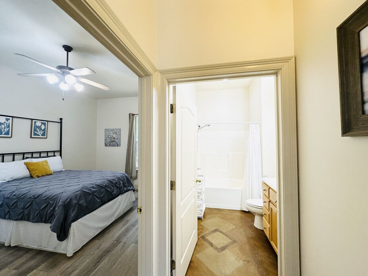 Un dormitorio con cama, ventilador de techo y baño con ducha y retrete.