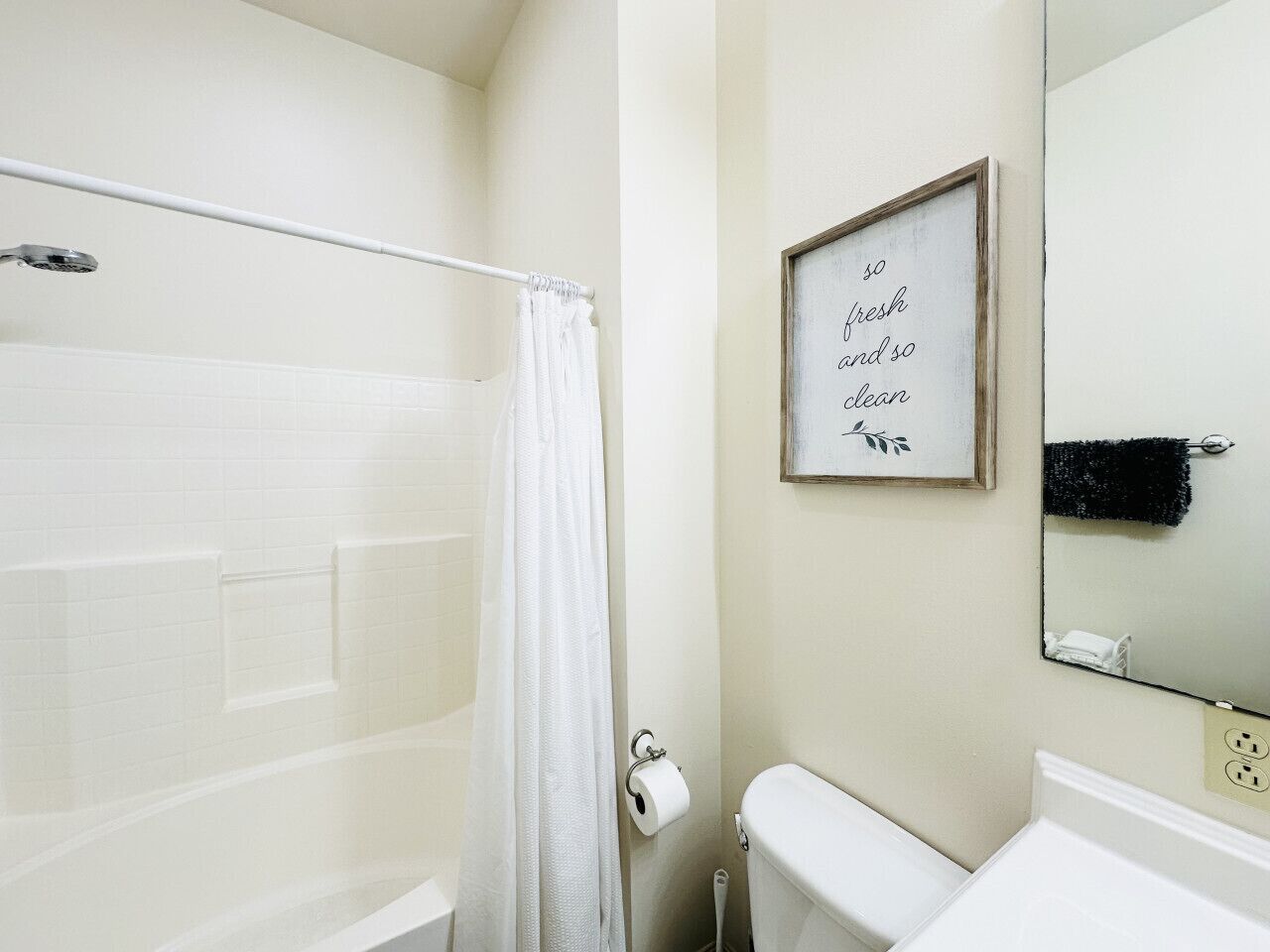 A bathroom with a shower, toilet, and a framed quote on the wall.