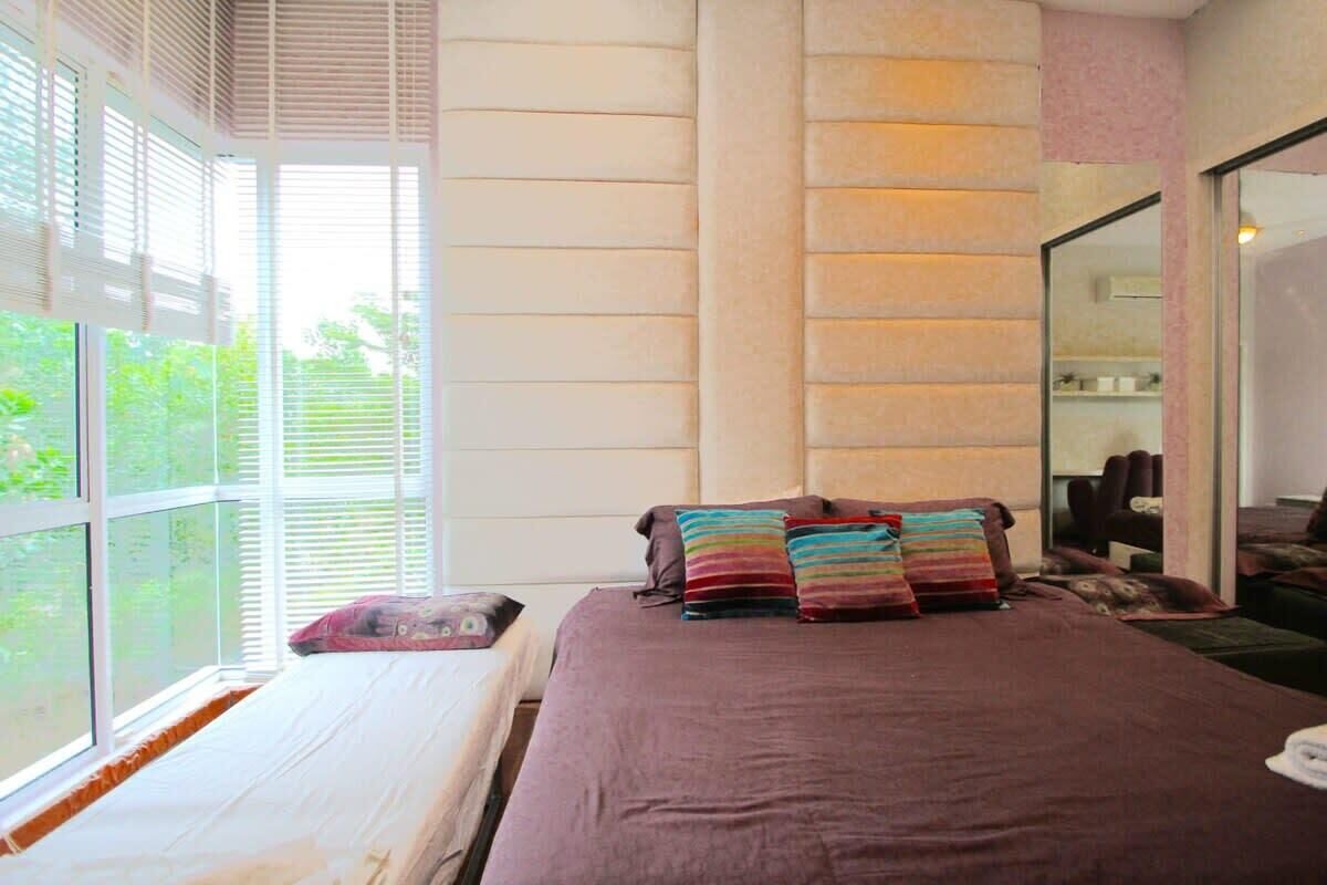 A bedroom with a large bed, a window with blinds, and a mirror on the wall.