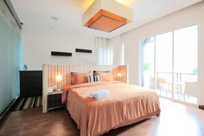 A modern hotel room with a large bed, a ceiling light fixture, and a view of the outdoors.