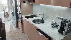 Une cuisine moderne équipée d’appareils électroménagers en acier inoxydable, d’un four encastré, d’un évier et d’une machine à café.