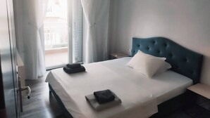 Une chambre d’hôtel avec un lit, une table de chevet, une fenêtre avec des rideaux et une vue sur l’extérieur.