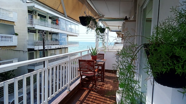 Un balcon doté d’un plancher en bois, d’une balustrade blanche et de plantes en pot.