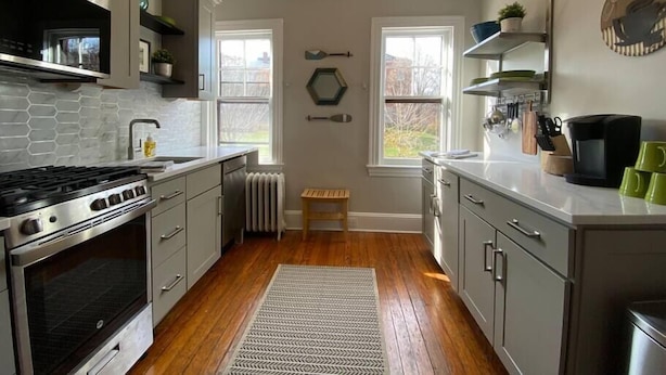 A modern kitchen with grey cabinets, a stainless steel stove, and a wooden floor. - Spectacular Location: State Circle Apartment (Annapolis)