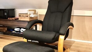 A modern chair with a wooden base and black upholstery in a room with wooden flooring and a skylight. - Cosy new Loft with bathroom and facilities (Glynneath)