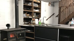 A modern kitchen with a central island, wooden shelves, a built-in oven, and a wooden staircase. - Cosy new Loft with bathroom and facilities (Glynneath)