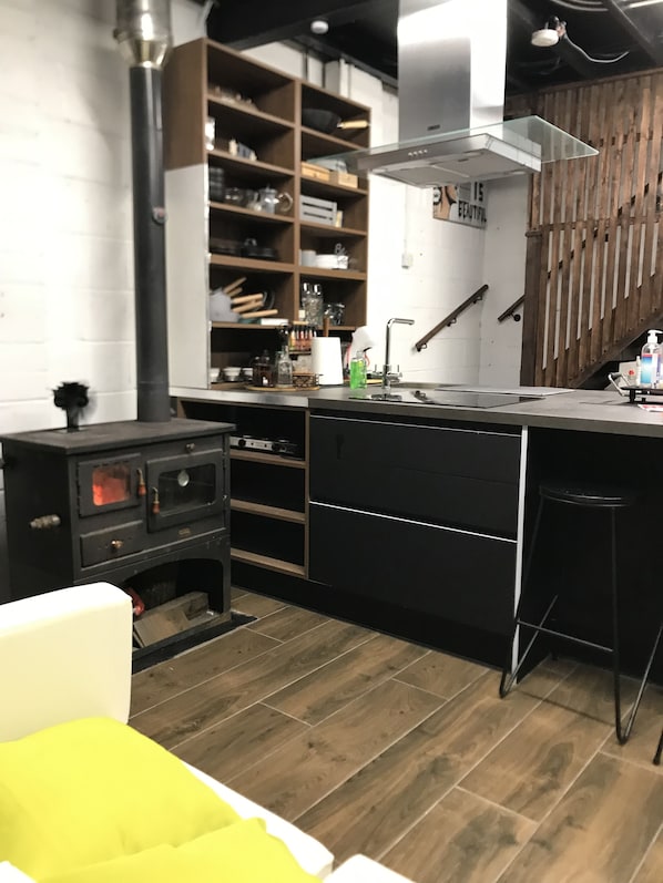 A modern kitchen with a central island, wooden shelves, a built-in oven, and a wooden staircase. - Cosy new Loft with bathroom and facilities (Glynneath)
