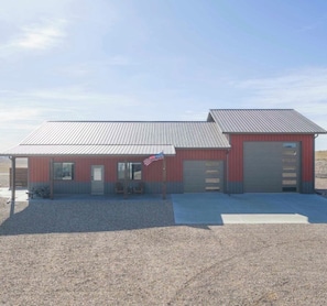 A building with a red exterior, a metal roof, and a flagpole with an American flag.