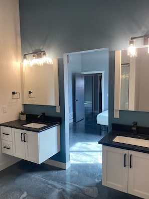 A modern bathroom with two sinks, large mirrors, and a walk-in shower.