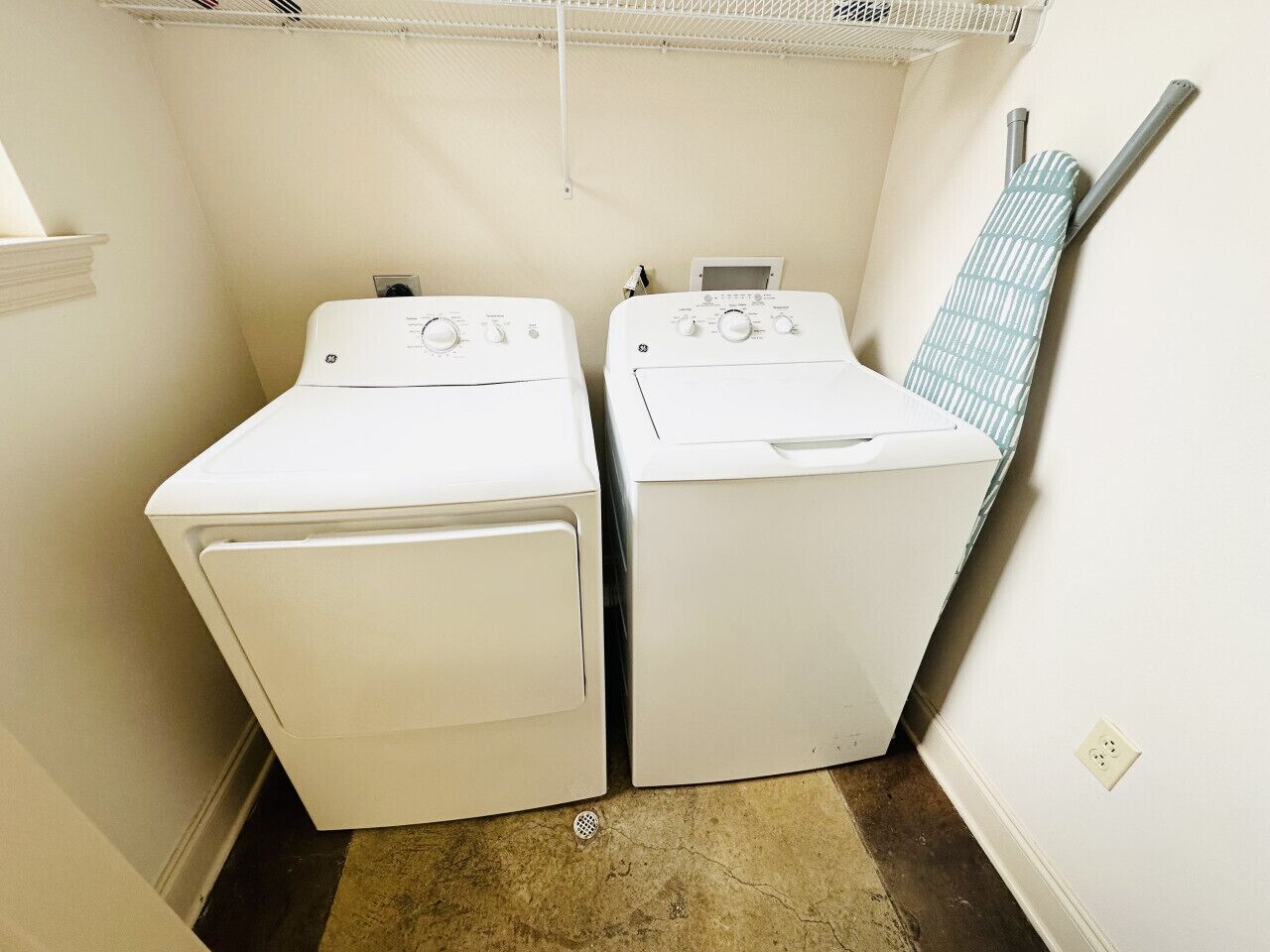 A laundry room with two white front-loading washing machines and a drying rack.