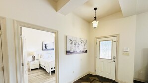 A hallway with a wooden floor, a white door, and a painting on the wall. - Chateau 7, spacious townhouse in Tickfaw, LA (Tickfaw)