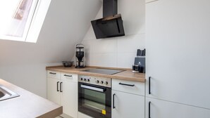 A modern kitchen with a built-in oven, a coffee maker, and a range hood.