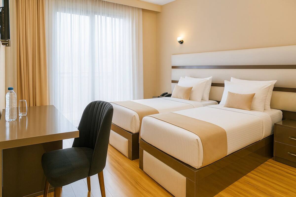 Una habitación de hotel con dos camas, un escritorio, una silla y una mesita de noche.