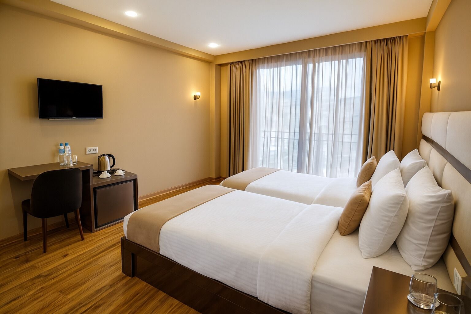 Habitació d'hotel amb dos llits, escriptori, cadira, televisió de pantalla plana i finestra amb cortines.