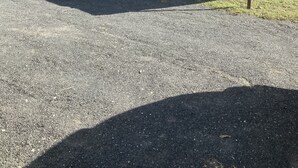 Un b âtiment métallique de plain-pied, doté de deux portes de garage, d’une allée gravillonnée et d’une végétation clairsemée en arrière-plan.