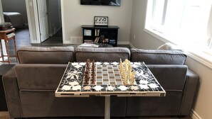 A living room with a chess table in front of a grey sofa.