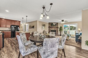 A spacious kitchen with wooden cabinets, a dining area with patterned chairs, and a fireplace.