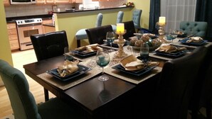 A dining area with a table set for four, surrounded by chairs, in a kitchen with wooden cabinets and a microwave. - DC  Townhouse  close to Capitol (Washington)