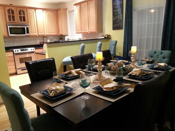 A dining area with a table set for four, surrounded by chairs, in a kitchen with wooden cabinets and a microwave.