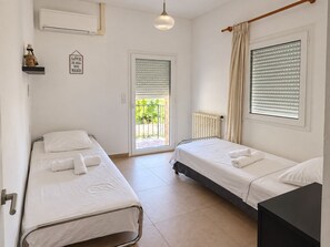 A hotel room with two single beds, a radiator, a ceiling light, a window with blinds, and a door leading to a balcony. - SPACIOUS VILLA  MIMOZA  (Montauroux)