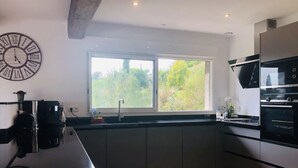 A modern kitchen with dark cabinets, a large window, and a built-in oven.