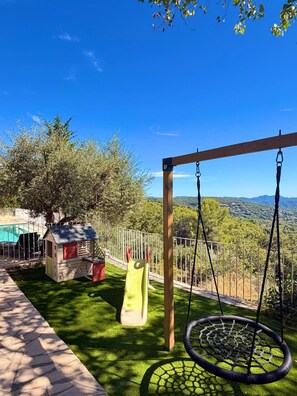 A backyard with a swing set, a slide, and a small playhouse. - SPACIOUS VILLA  MIMOZA  (Montauroux)