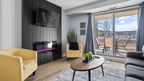 A modern living room with a flat-screen TV, a fireplace, and a large sliding glass door to an outdoor patio.