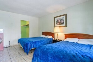 Two single beds with blue bedspreads, a wooden headboard, and a framed picture adorn this cozy space.