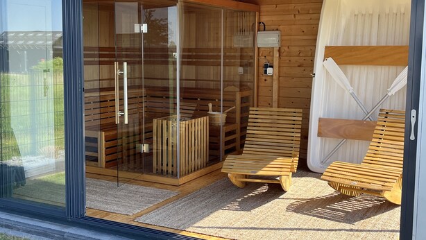 Een moderne sauna met glazen deuren, houten banken en een houten sauna-cabine.
