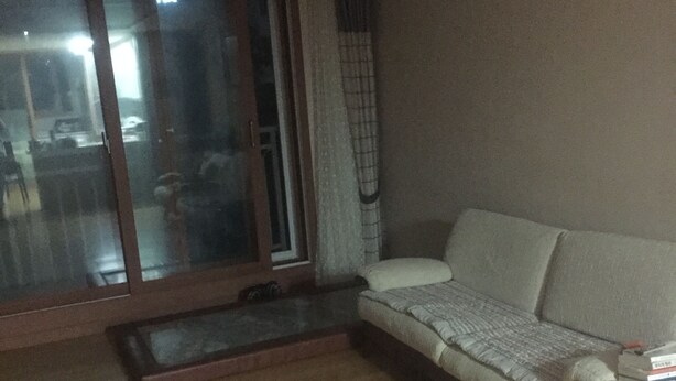 Ein Wohnzimmer mit einer Couch, einem kleinen Tisch und einer Glastür zum Balkon.