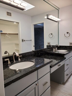 A modern bathroom with two sinks, a large mirror, and a shower visible through an open door. - Tennis, Greenbelt, Private Courtyard Patio, Clean, Pet Friendly, Family Friendly (Scottsdale)