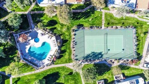 Ovenfra set et boligområde med swimmingpool, tennisbane og grøn beplantning omkring.