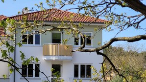 A two-story building with a red-tiled roof, a balcony with a wooden railing, and multiple windows. - Strandnest holiday apartment (Karlshagen)