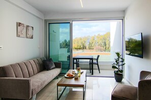 A modern living room with a sofa, a coffee table, a dining table, and a potted plant.