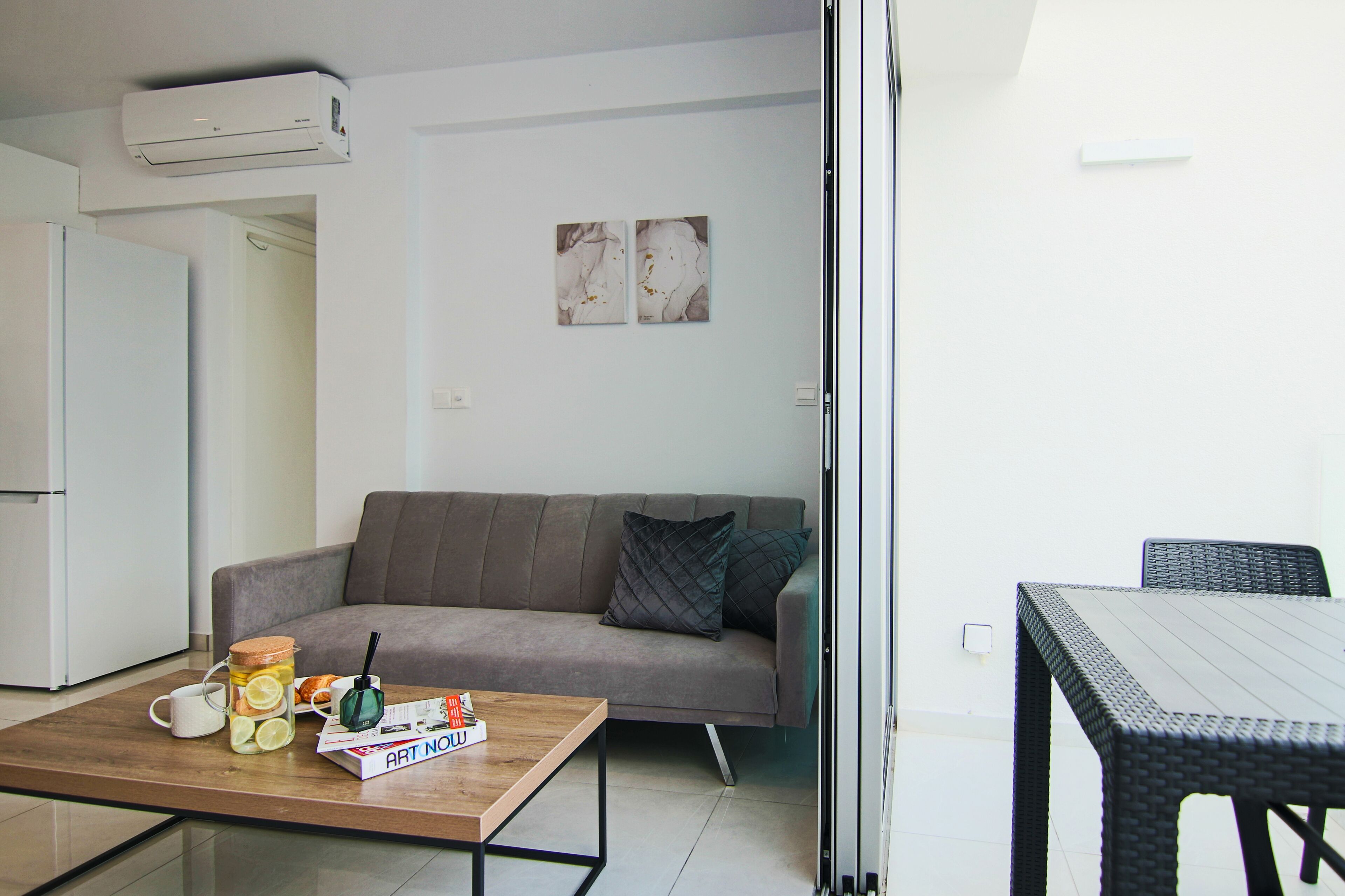 A modern living room with a sofa, coffee table, and a dining area with a table and chairs.