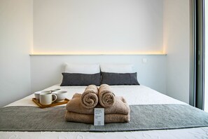 A neatly made bed with rolled towels, a tray with cups, and a thank you note.