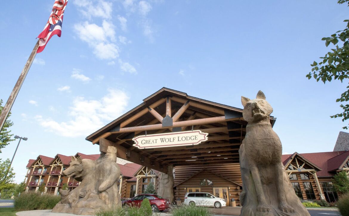 Een lodge met een opvallend wolfbeeld, een bord met de tekst 'Great Wolf Lodge' en een vlaggenmast met een vlag.