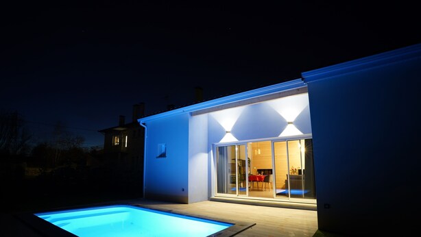 Una casa moderna con piscina y un patio bien iluminado.