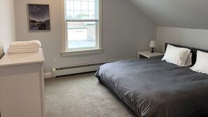 Ein Schlafzimmer mit einem großen Bett, einem Nachttisch, einem Fenster und einem Handtuch auf einer Ablagefläche.