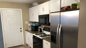 A compact kitchen with white cabinets, a stainless steel refrigerator, a microwave, a stove, and a coffee maker. - 1220 Hartford Avenue <br> Previous 4 star owner , Airbnb<br>Happy New Year to All (Atlanta)