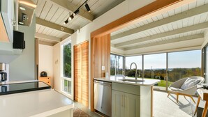 A modern kitchen with a large island, wooden cabinets, and a view of the outdoors.