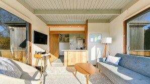 A modern interior with a sofa, a small table, a TV, and a kitchen area.