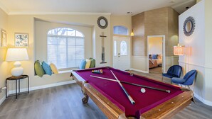 A pool table in a room with a window, a lamp, and a mirror on the wall. - New! Cozy Modern Pool Home, Close to Downtown and The Strip (North Las Vegas)