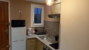 Una cucina compatta con forno a microonde, macchina del caffè, lavello e finestra.