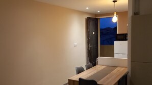 Una cucina moderna con zona pranzo, che include un tavolo e sedie in legno, un forno a microonde nero e un frigorifero bianco.