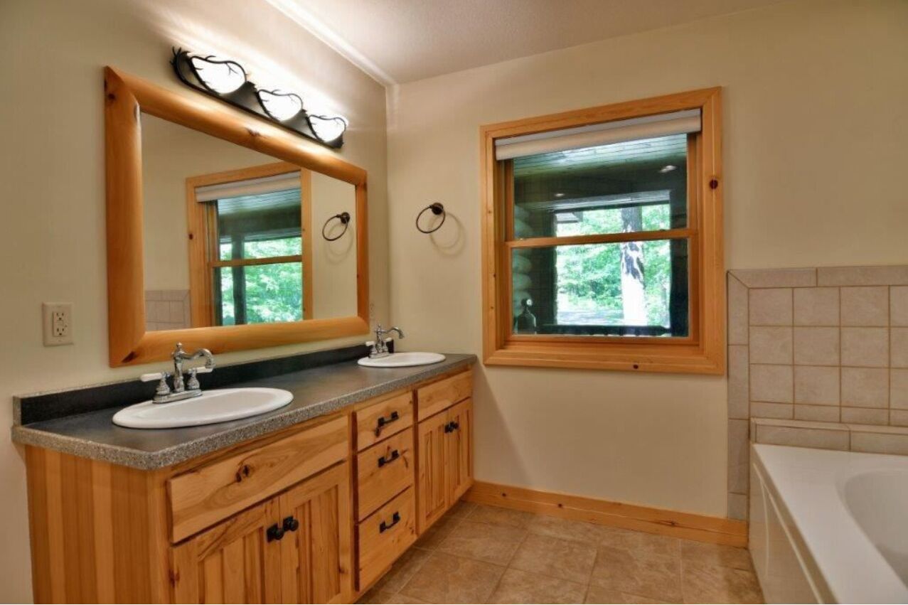 Un baño con dos lavamanos, un espejo grande y una ventana.