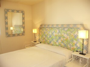 A hotel room with a bed, two bedside tables, a nightstand, a lamp, a mirror, and a patterned headboard. - Apartment in Carabeo near Burriana beach (Nerja)