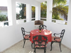 A dining area with a round table, four chairs, and a bottle of wine. - Apartment in Carabeo near Burriana beach (Nerja)
