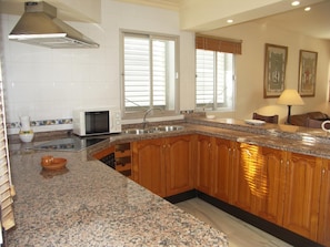 A kitchen with granite countertops, wooden cabinets, a microwave, and a sink. - Apartment in Carabeo near Burriana beach (Nerja)